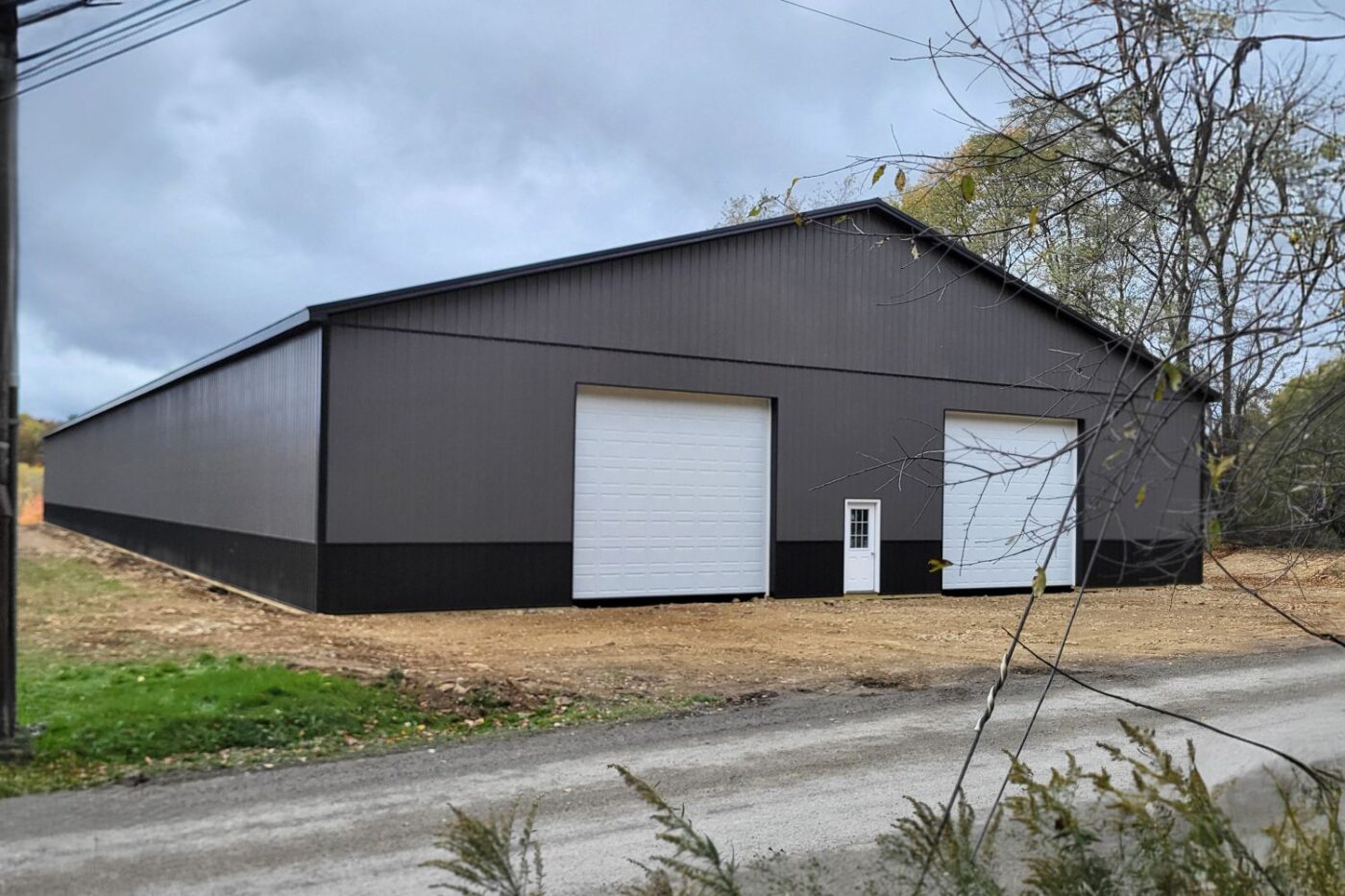 Exterior view of completed 80x200 Garage in Brackney PA. Gray and Black siding and trim with white garage and single door.