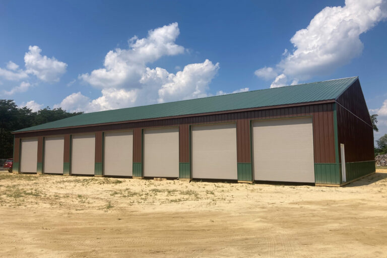 brown pole barn garage with green trim and six white garage doors edited